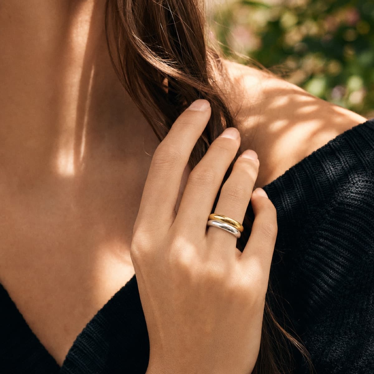 The Bold ring stack in gold and rhodium worn in dappled garden light