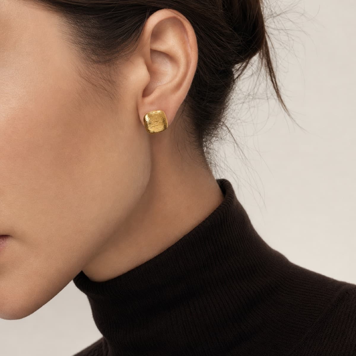 The Echo earrings in gold worn with a brown turtleneck